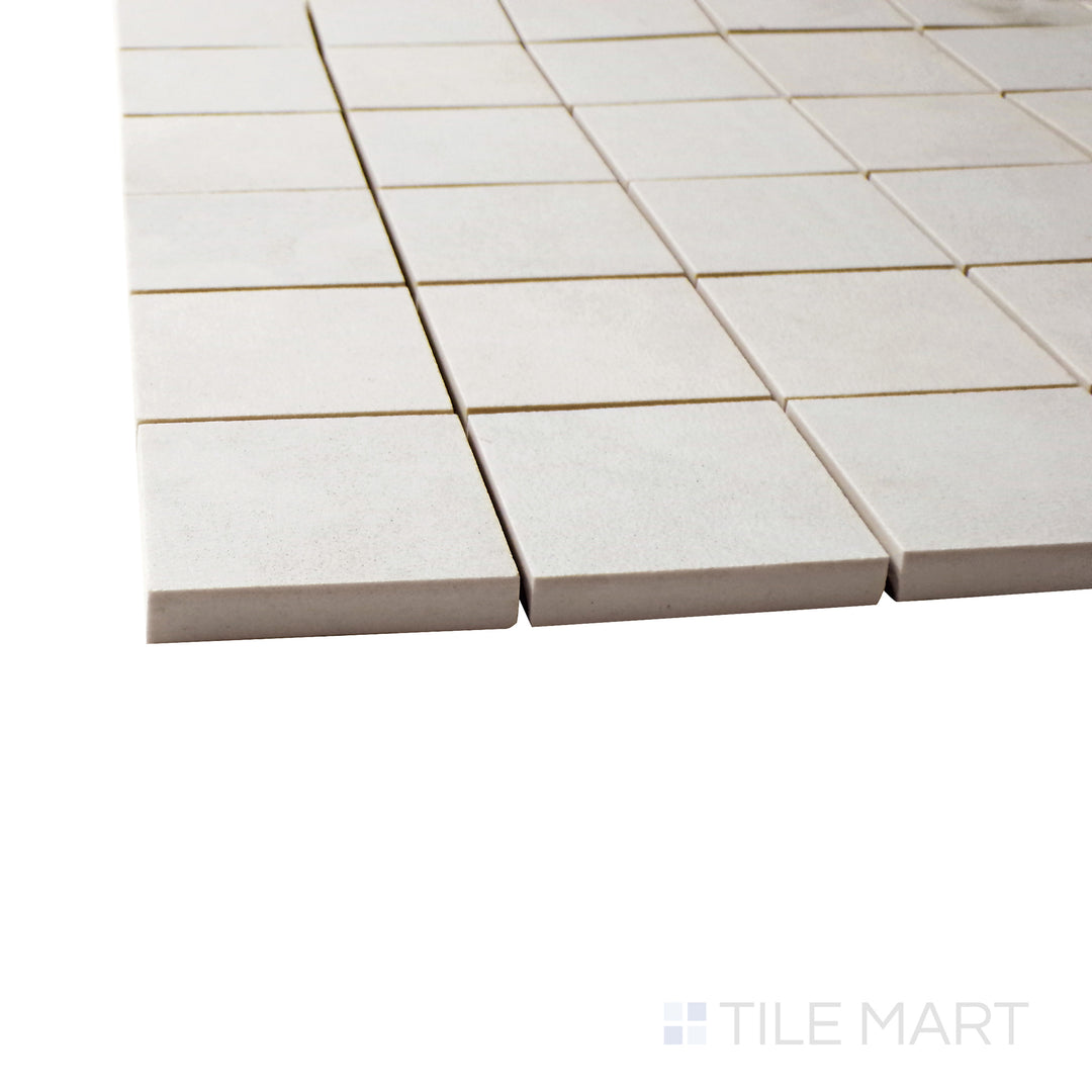 A corner shot of the Creos Bride 2" square matte porcelain mosaic tile highlights its bright white tone and structured grid pattern, offering a clean and refined finish for accent areas.