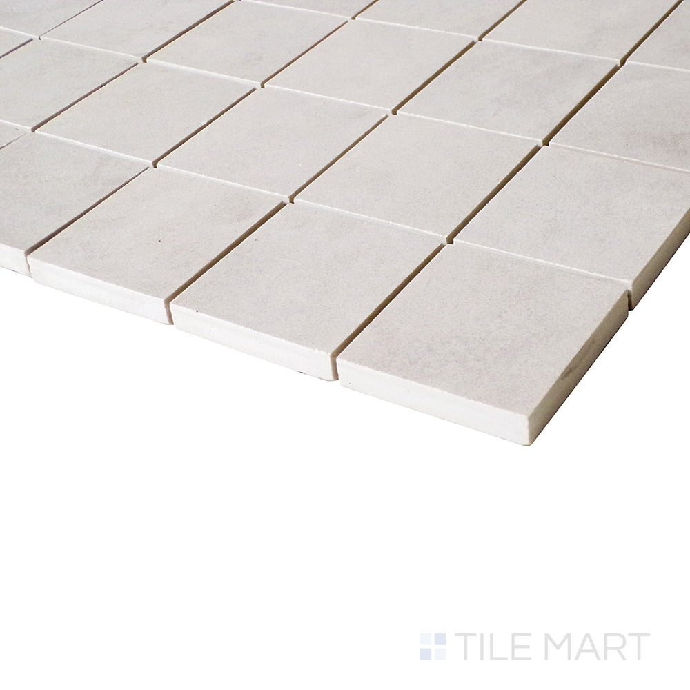 An angled perspective captures the soft tones and precise pattern of this square mosaic tile, adding depth to its matte finish.