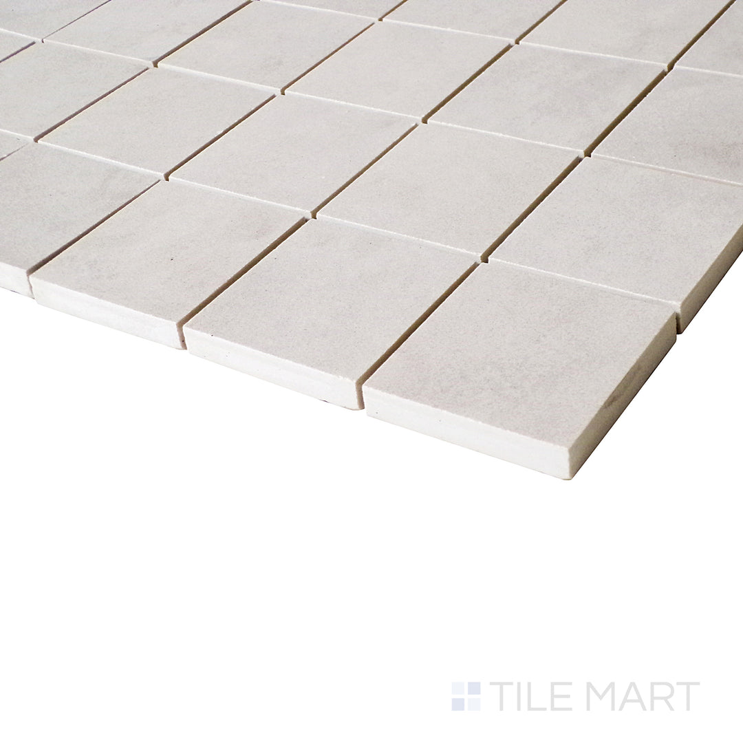 An angled perspective captures the soft tones and precise pattern of this square mosaic tile, adding depth to its matte finish.