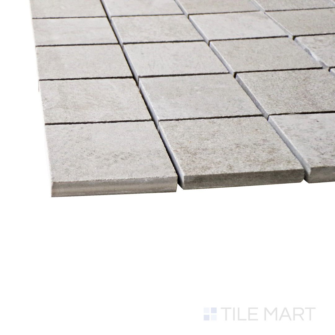 Captured from a corner angle, the Ecocrete Aqua 2" square matte porcelain mosaic tile showcases its subtle aqua tones and structured square layout, ideal for adding texture and depth to surfaces.