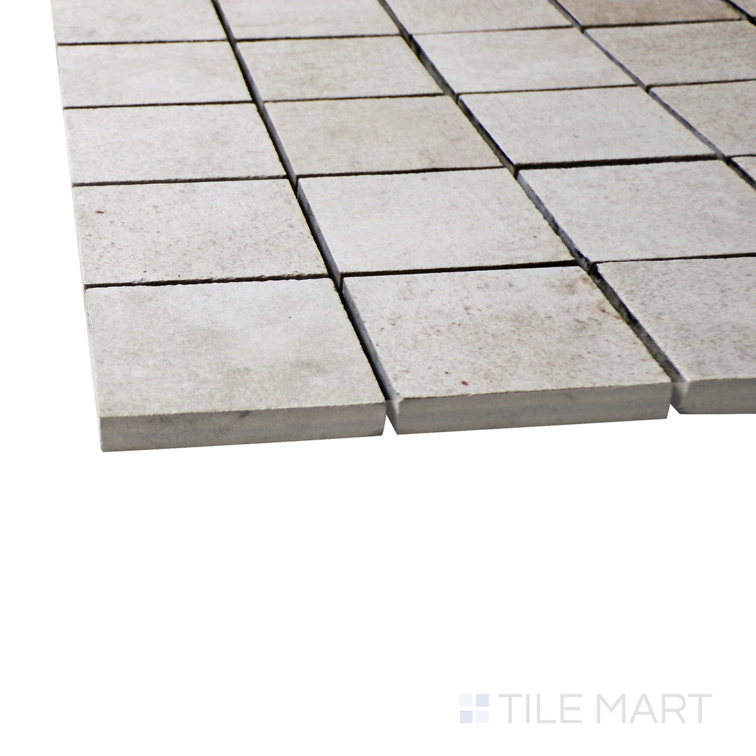 A corner perspective of the Ecocrete Melted Ice 2" square matte porcelain mosaic tile emphasizes its cool gray shade and crisp square pattern, perfect for creating a sleek and refined design.