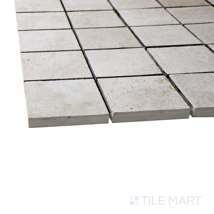 A corner perspective of the Ecocrete Melted Ice 2" square matte porcelain mosaic tile emphasizes its cool gray shade and crisp square pattern, perfect for creating a sleek and refined design.