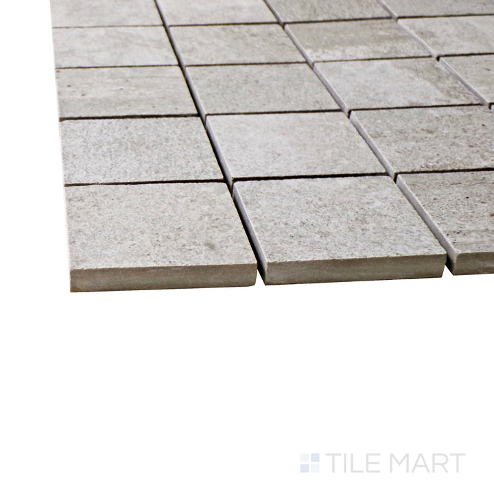 A corner shot of the Ecocrete Sage 2" square matte porcelain mosaic tile highlights its natural green tones and matte finish, offering a stylish and organic feel to tiled spaces.