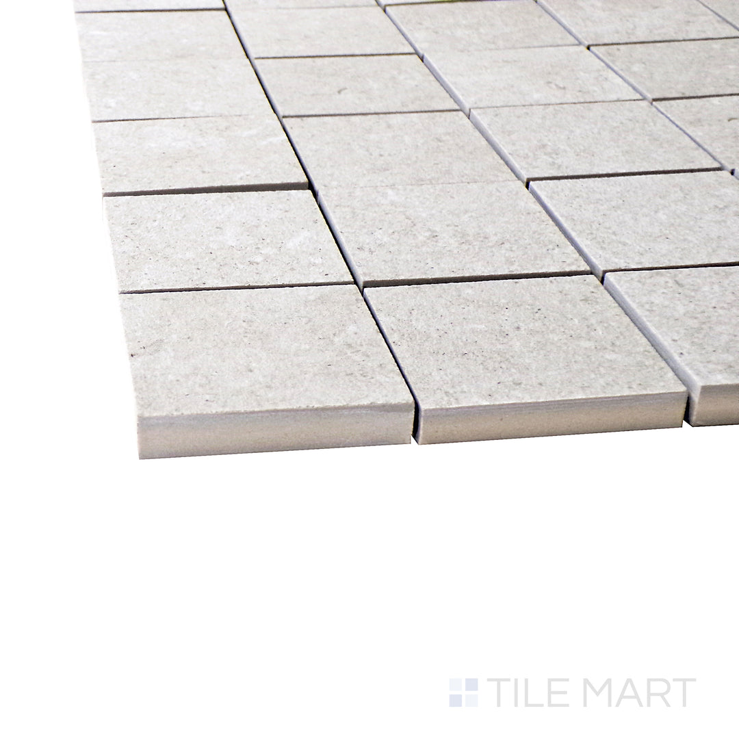 A corner perspective of the Epika Almond 2" square matte porcelain mosaic tile emphasizes its warm almond tones and uniform grid layout, adding depth and texture to tiled surfaces.