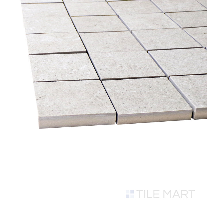 A corner perspective of the Epika Almond 2" square matte porcelain mosaic tile emphasizes its warm almond tones and uniform grid layout, adding depth and texture to tiled surfaces.