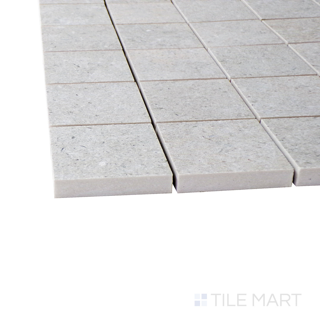 Captured from a corner angle, the Epika Shell 2" square matte porcelain mosaic tile showcases its warm neutral tones and precise square design, offering a refined and subtle aesthetic.