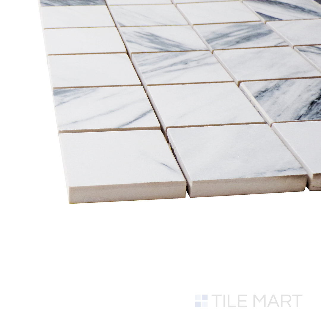 A corner perspective of the Exotic Stone Cosmopolitan Statuario Fantastico 2" square polished porcelain mosaic tile emphasizes its striking marble-inspired veining and reflective finish, ideal for elegant spaces.