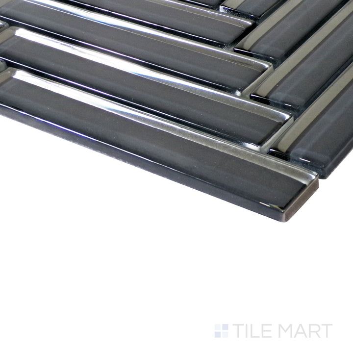 A close-up angle enhances the deep black hues of the herringbone glass mosaic, while light dances across its glossy surface.