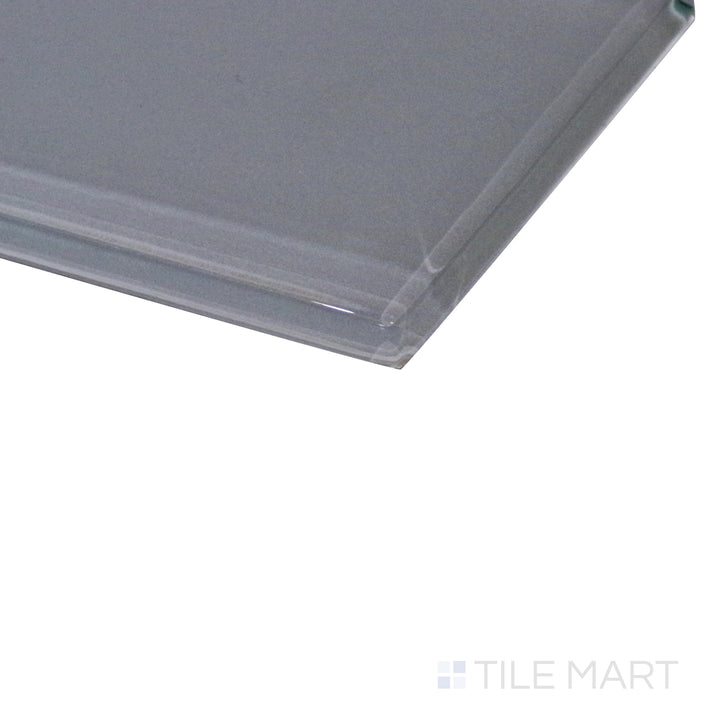 A modern pastel grey glass tile reflects ambient light, with an angled view showcasing its smooth, glossy surface.