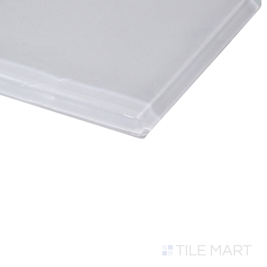 A smooth pastel white glass tile shines under soft lighting, with an angled shot emphasizing its glossy texture and sleek appeal.