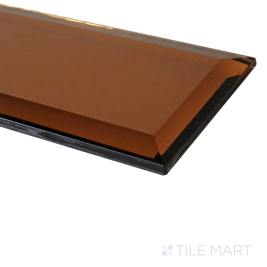 A beveled copper glass tile catches the light at an angle, emphasizing its rich metallic sheen and polished glossy surface.