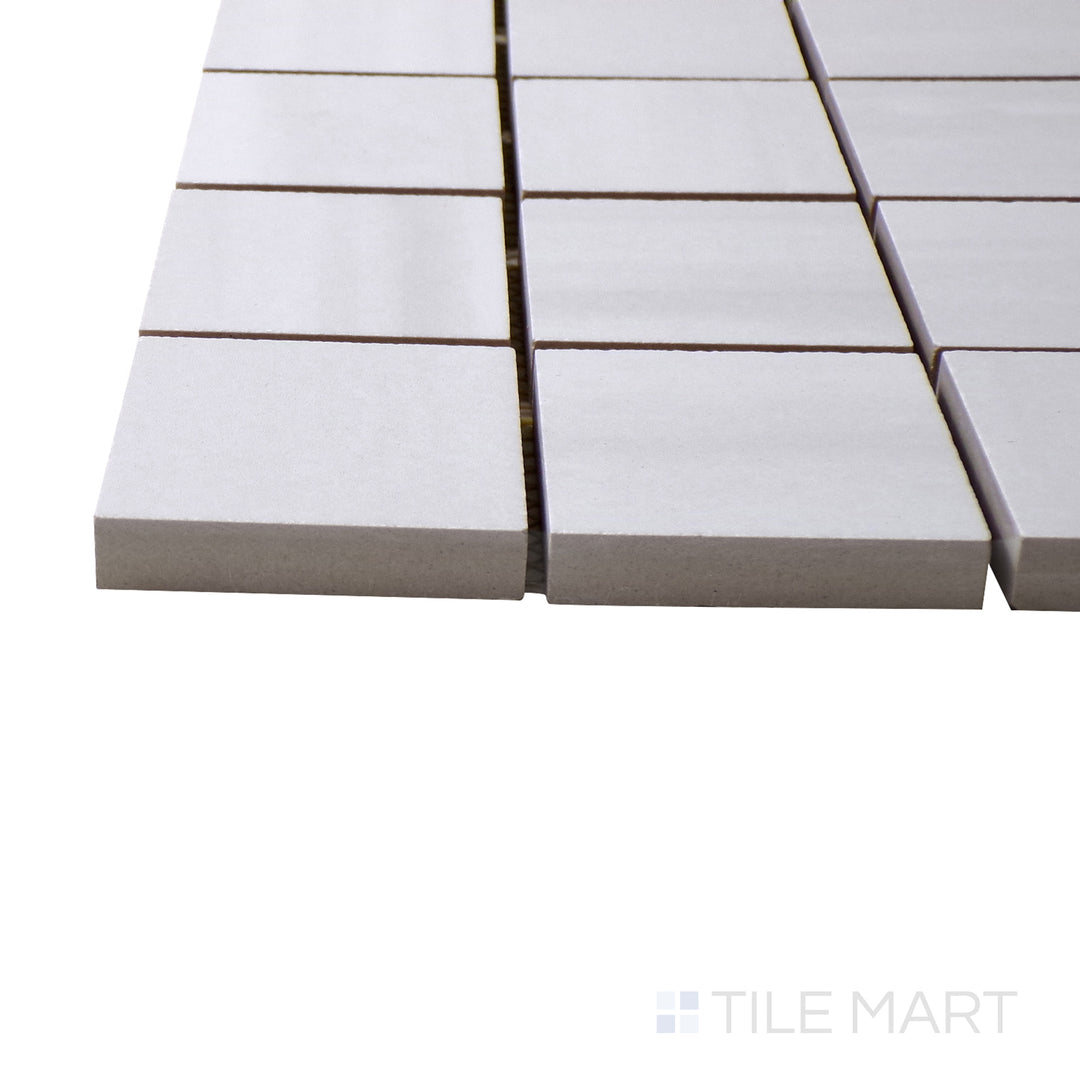 Captured from a corner angle, the Luxury Deodat White 2" square polished porcelain mosaic tile showcases its clean white color and polished sheen, enhancing designs with a bright and modern accent.