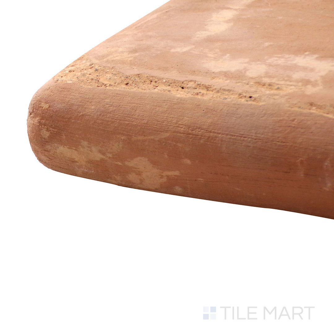 Captured from a corner angle, the Saltillo Salmon 12x12 stair coping corner natural terracotta tile showcases its curved form and handcrafted surface, ensuring a smooth transition for stair designs.
