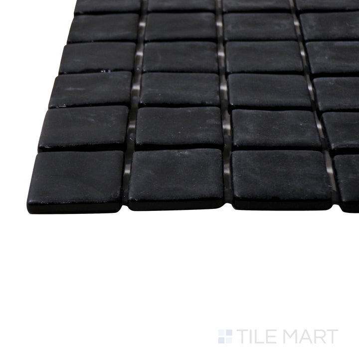 A corner perspective of the Natureglass Malla Black 1" square matte glass mosaic tile emphasizes its deep black tone and smooth matte finish, ideal for bold and modern accents.