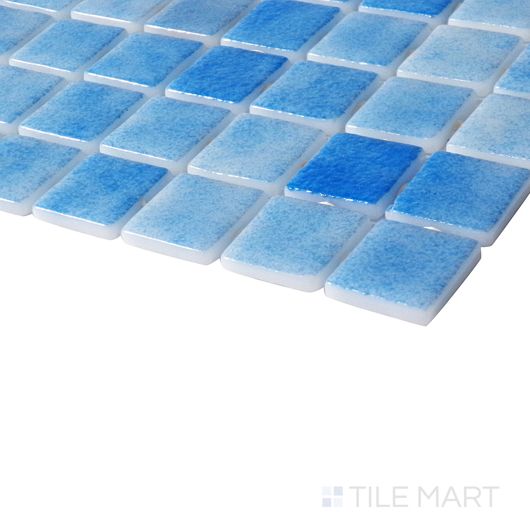 Angled close-up capturing the soft, icy tones of Nieve Celeste 1" square glossy glass mosaic.