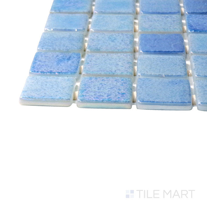 Captured from a corner angle, the Opalescent Mix Azul 1" square glossy glass mosaic tile showcases a blend of blue shades with a glossy shimmer, adding depth and dynamic visual interest.