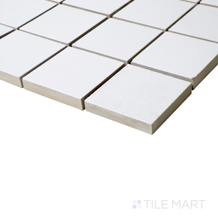 Angled close-up showcasing the subtle matte texture of Pearl Super White 2" square porcelain mosaic.
