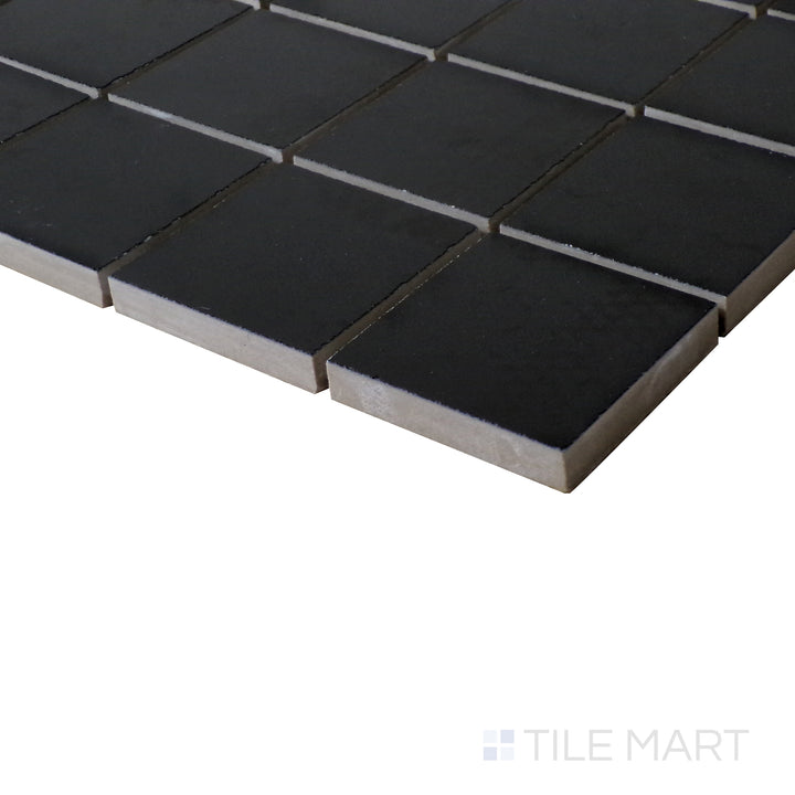 Tilted view highlighting the dramatic contrast of Pearl Super Black 2" square polished porcelain mosaic.