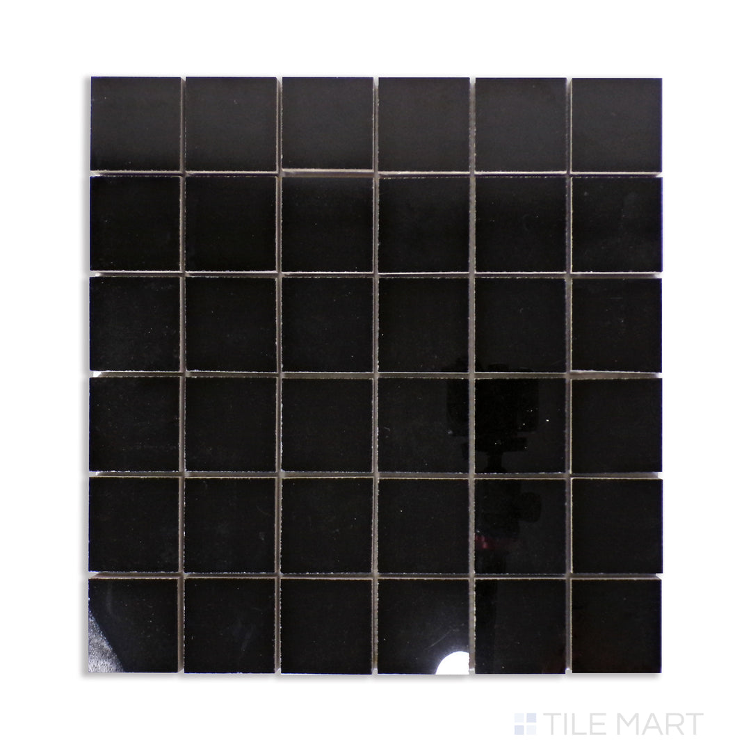 A mosaic of deep black polished porcelain tiles in a 2-inch square pattern, arranged seamlessly and displayed from an overhead angle for maximum detail.