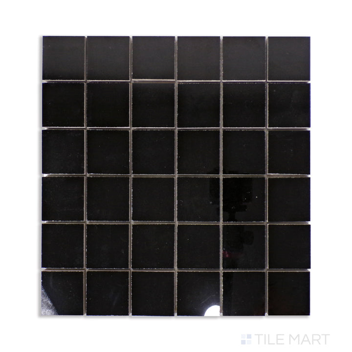 A mosaic of deep black polished porcelain tiles in a 2-inch square pattern, arranged seamlessly and displayed from an overhead angle for maximum detail.