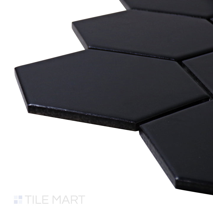 A corner shot of the Porcelain Glazed Mosaics Black 4" hexagon matte tile emphasizes its large hexagonal design and deep black finish, ideal for creating a bold statement.