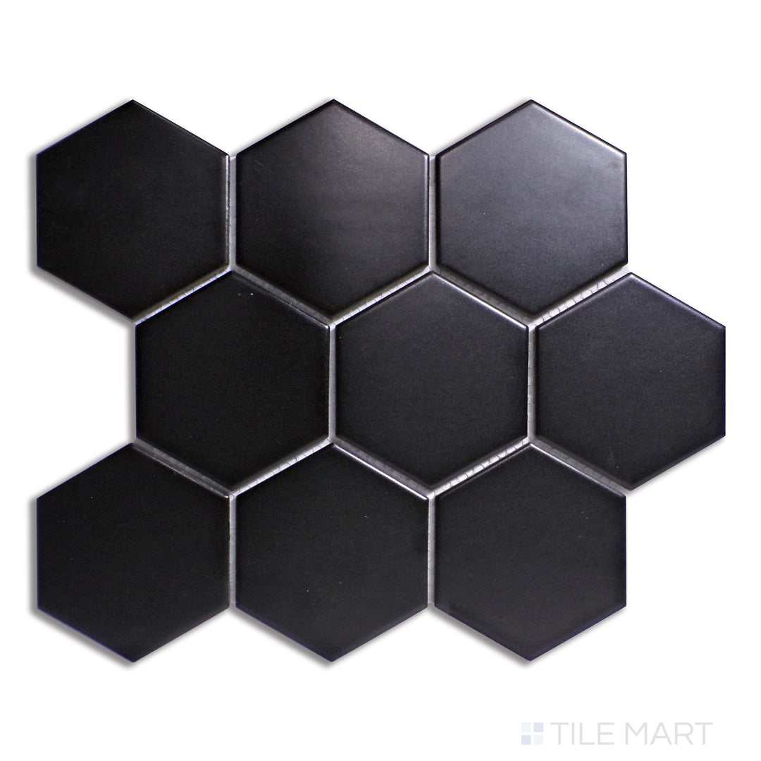 A dramatic black 4-inch hexagonal matte porcelain tile, featuring a bold, large-scale honeycomb structure, captured from a top-down view for clarity.