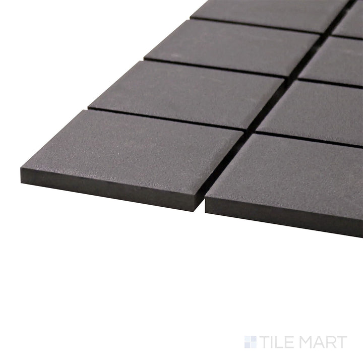A corner shot of the Solids Black 2" Square Matte Porcelain Mosaic tile showcases its classic square shape and deep black matte finish for a versatile and sleek design.
