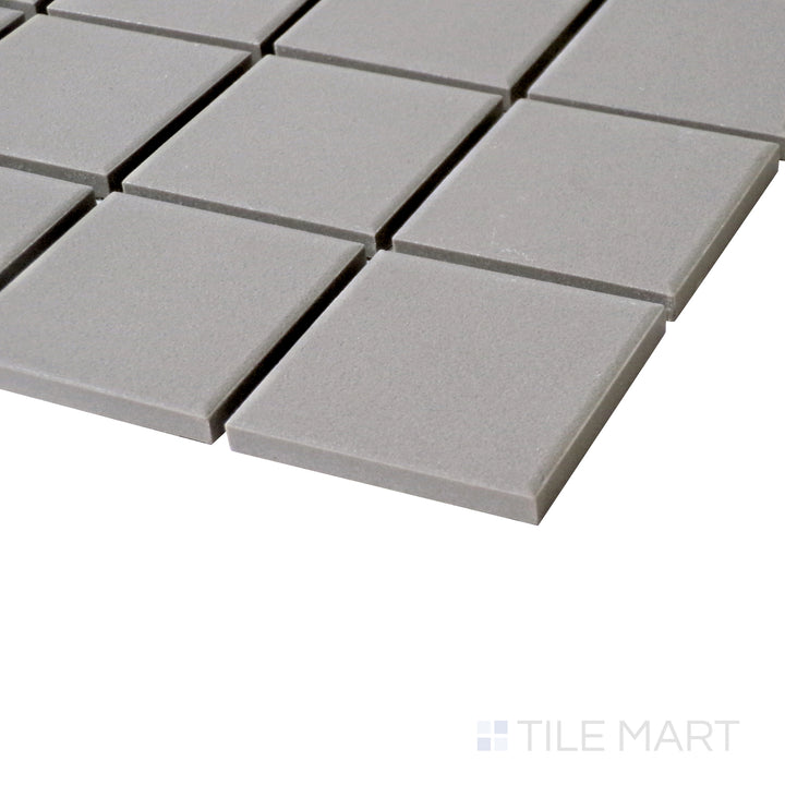 An angled perspective focusing on the soft, neutral hues and minimalist grid pattern of Solids Gray 2" Square Matte Porcelain Mosaic.