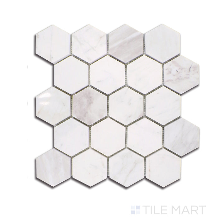 A refined top-down view of Volakas marble in a compact 2.5-inch hexagon layout, exhibiting soft white tones interwoven with intricate gray veining, finished with a glossy polish.
