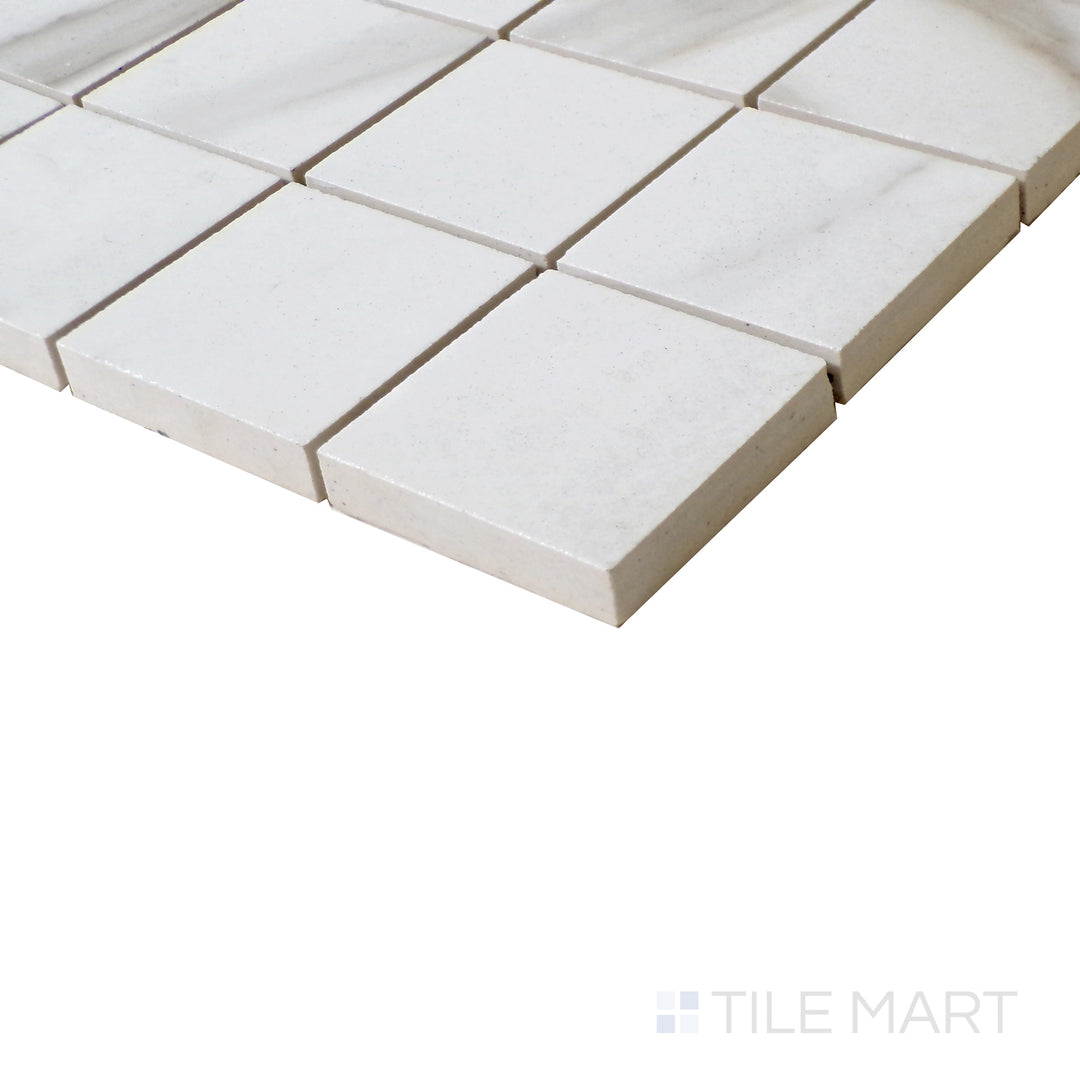 Angled shot of Tele Di Marmo Reloaded Calacatta 2" Square matte porcelain mosaic, featuring a refined white base, delicate veining, and a structured square layout.  