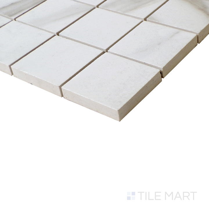 Angled shot of Tele Di Marmo Reloaded Calacatta 2" Square matte porcelain mosaic, featuring a refined white base, delicate veining, and a structured square layout.  