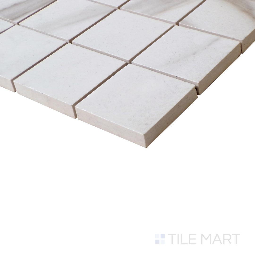 Slanted perspective of Tele Di Marmo Reloaded Calacatta 2" Square polished porcelain mosaic, emphasizing its crisp white tones, delicate veining, and high-gloss polished finish.  