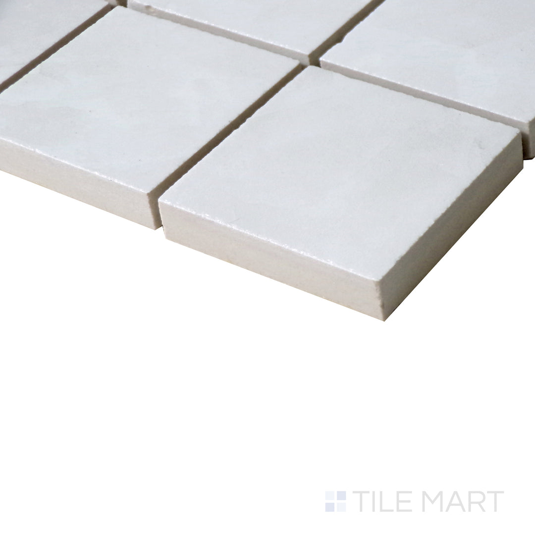 Angled shot of Tele Di Marmo Revolution Thassos 2" Square polished porcelain mosaic, featuring its bright white tones, smooth texture, and a radiant polished finish.  
