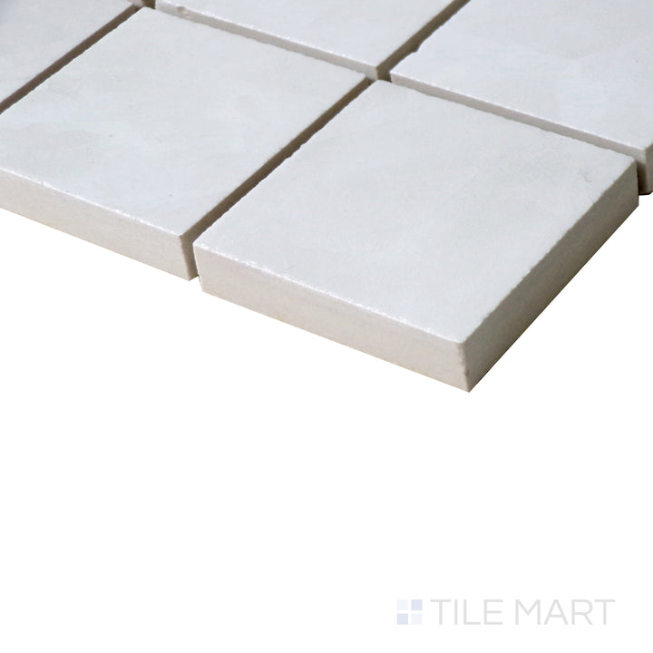 Angled shot of Tele Di Marmo Revolution Thassos 2" Square polished porcelain mosaic, featuring its bright white tones, smooth texture, and a radiant polished finish.  