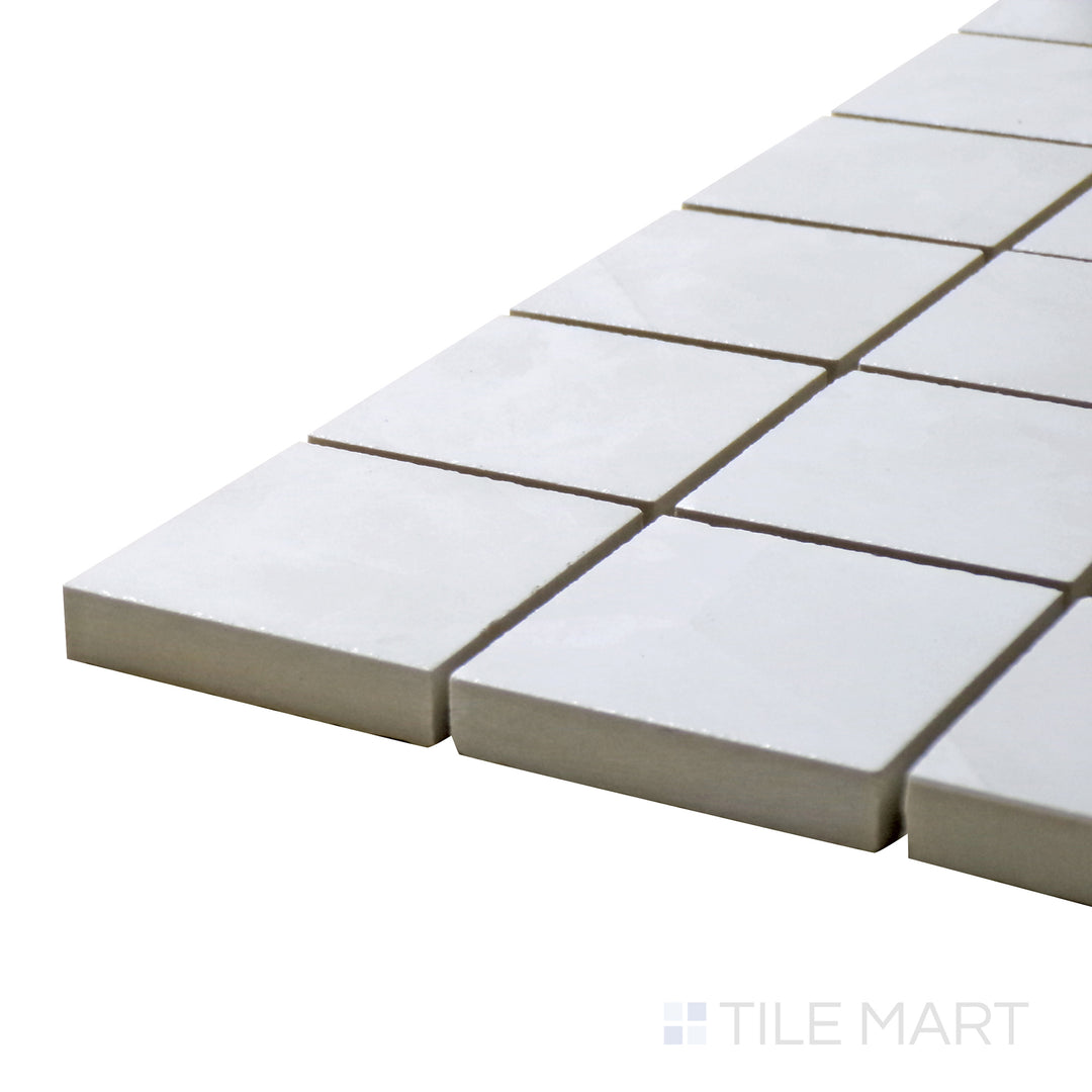 Angled view of Tele Di Marmo Revolution Thassos 2" Square Polished Porcelain Mosaic, showcasing its radiant white marble design with a highly reflective polished finish.