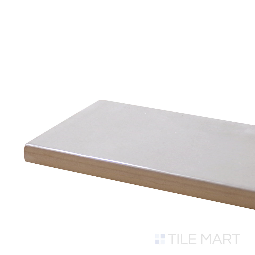 Angled view of Village Silver Mist 2.5X8 Glossy Ceramic Tile, highlighting its soft silver-gray hue with a sleek glossy finish.