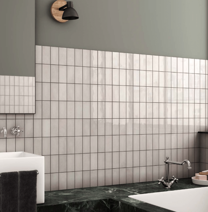 A sleek, modern setting with Village Silver Mist 2.5X8 Glossy Ceramic, offering a cool-toned neutral palette with a glossy finish that enhances depth and light reflection.