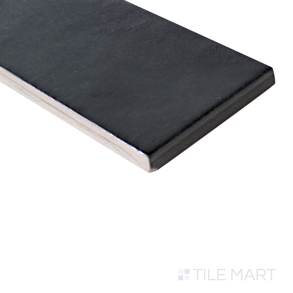 Angled shot of Village Black 2.5x8 glossy ceramic tile, highlighting its deep black shade, sleek glossy sheen, and structured rectangular shape.  