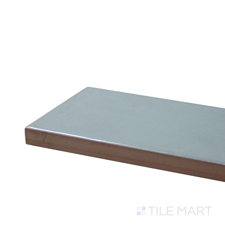 Side perspective of Village Cloud 2.5X8 Glossy Ceramic Tile, capturing its soft neutral gray hue with a glassy, smooth texture.