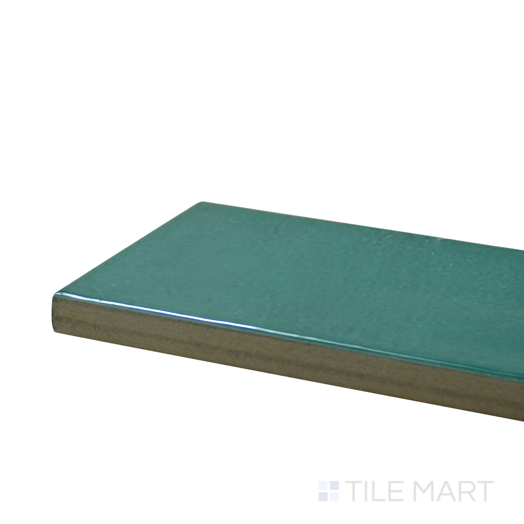 Angled close-up of Village Emerald Green 2.5X8 Glossy Ceramic Tile, showcasing its rich green tones with a polished surface for a luxurious look.