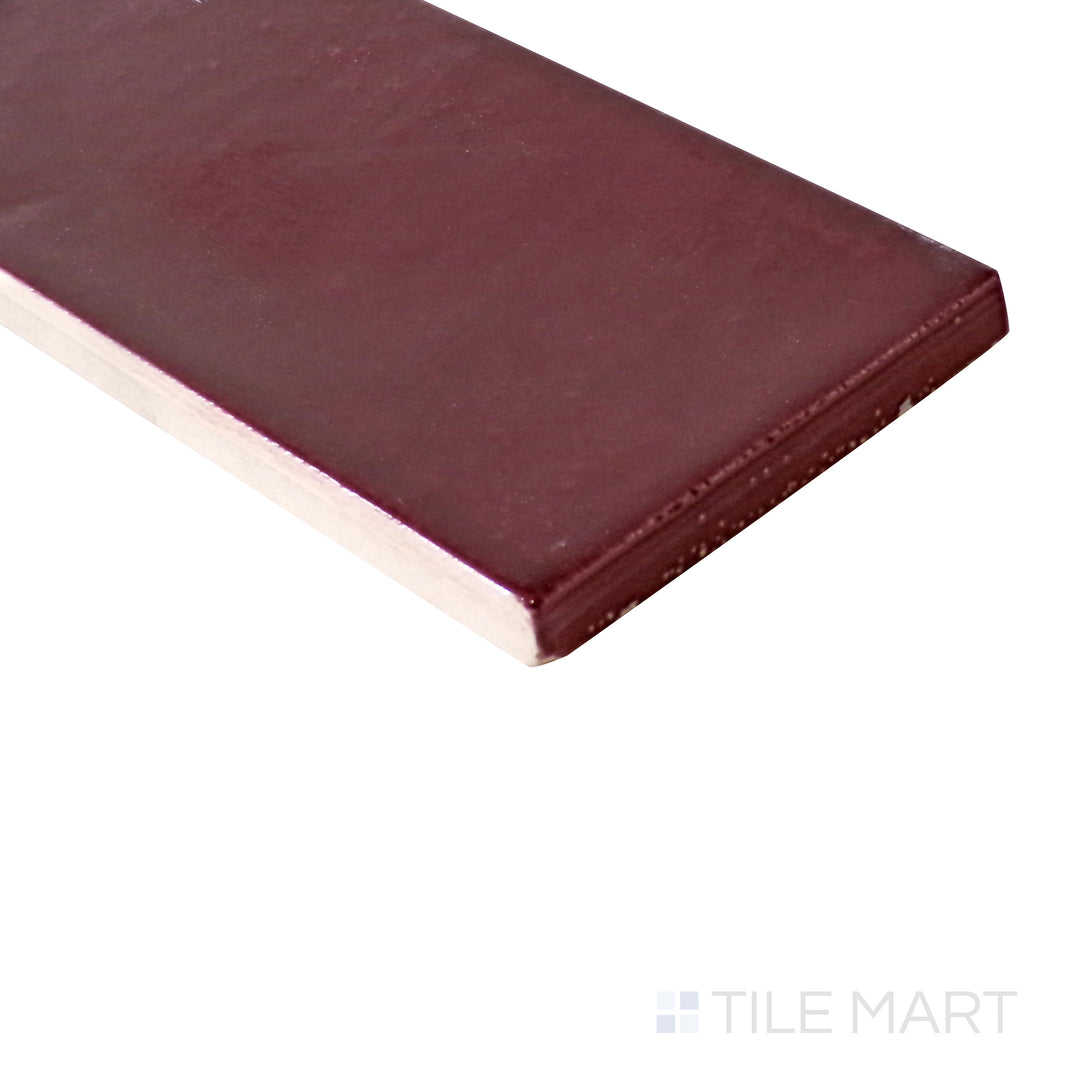 Angled view of Village Aubergine 2.5x8 glossy ceramic tile, highlighting its deep purple tone, glossy polished finish, and elongated rectangular form.  