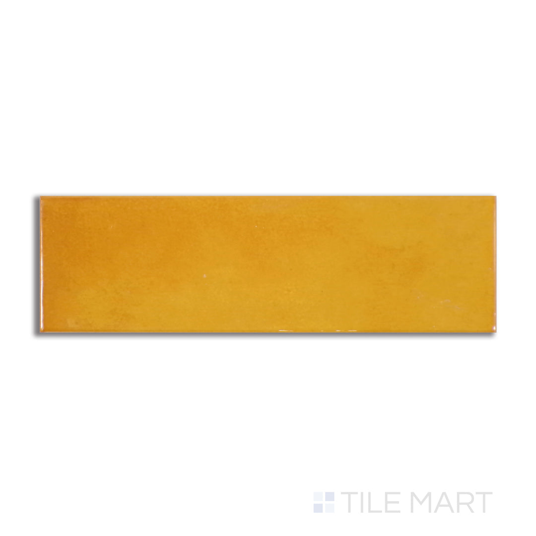 Flat-lay image of Village Tuscany Gold 2.5X8 glossy ceramic tile, exuding warmth with its golden hues and reflective surface reminiscent of sunlit landscapes.