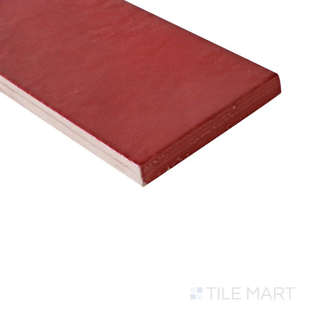 Diagonal view of Village Volcanic Red 2.5x8 glossy ceramic tile, showcasing its vibrant red tones, polished glossy sheen, and structured rectangular format.  