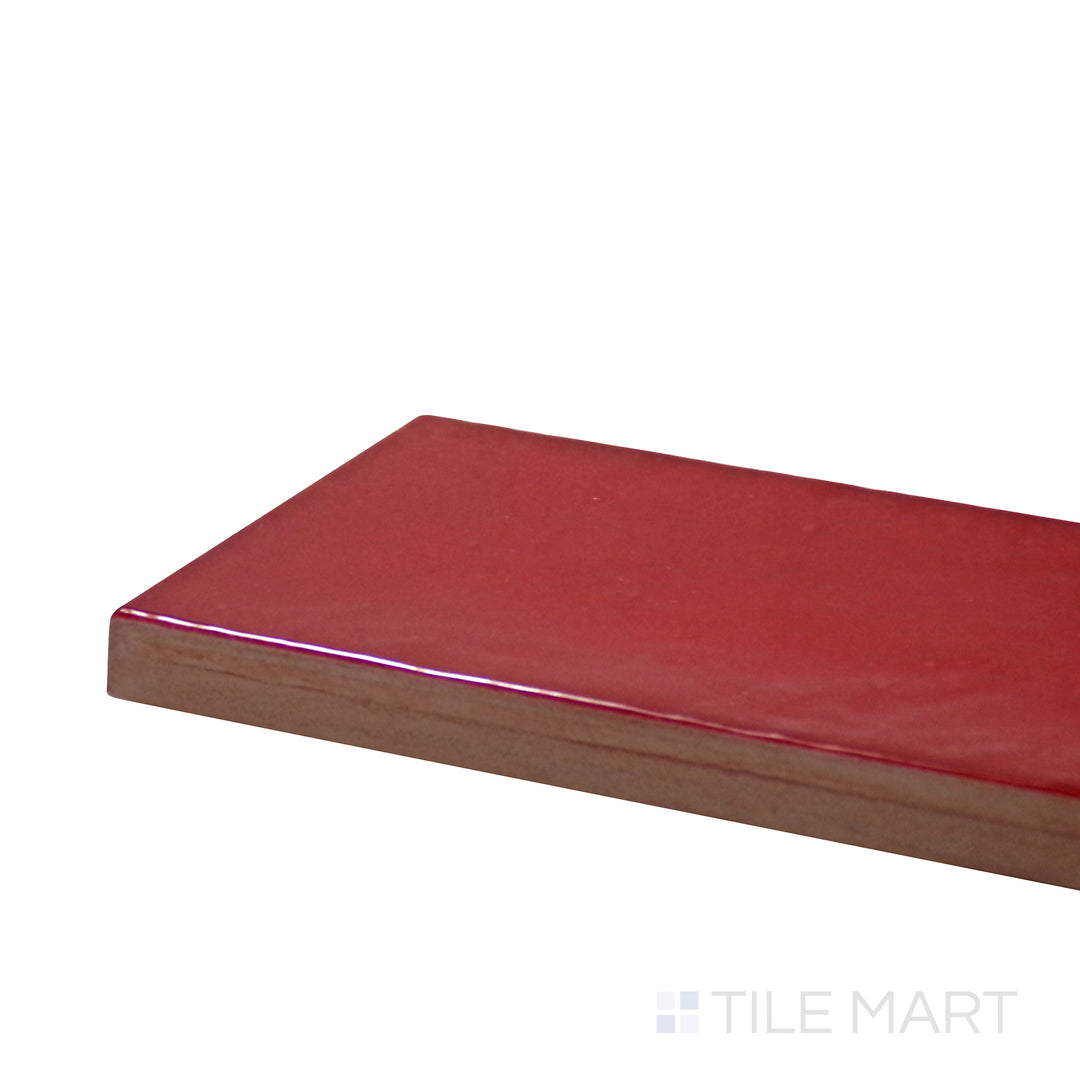 Corner-focused shot of Village Volcanic Red 2.5X8 Glossy Ceramic Tile, highlighting its fiery red tones with a reflective high-gloss texture.