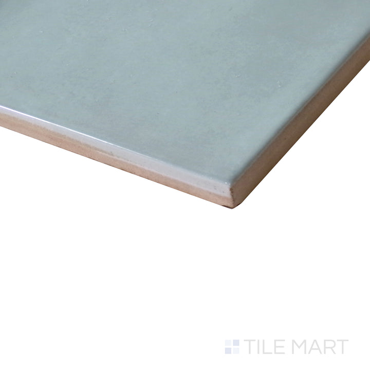 Angled shot of Village Mint 5x5 glossy ceramic tile, featuring a soft mint green hue, reflective polished surface, and classic square shape.  