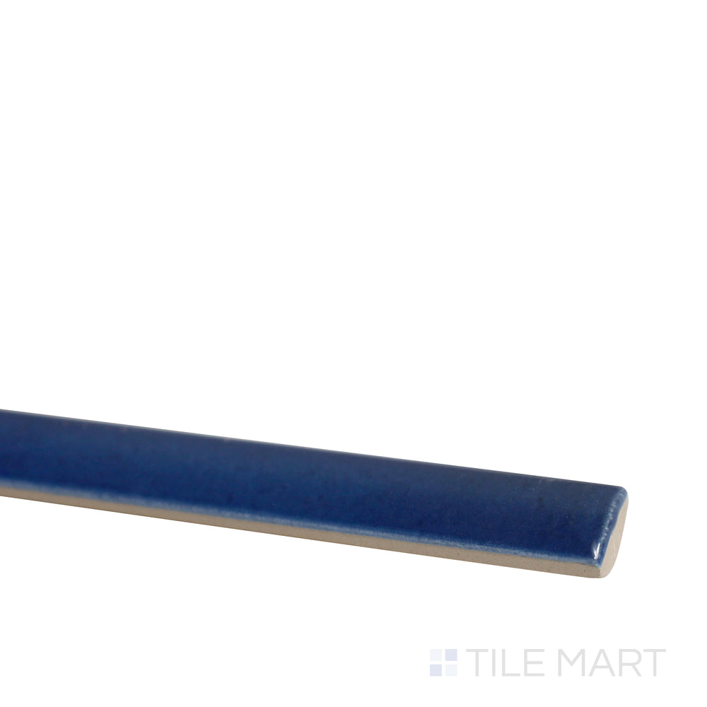 Diagonal view of Village Royal Blue 0.5x8 glossy ceramic jolly tile, showcasing its bold blue shade, smooth texture, and decorative trim format.  