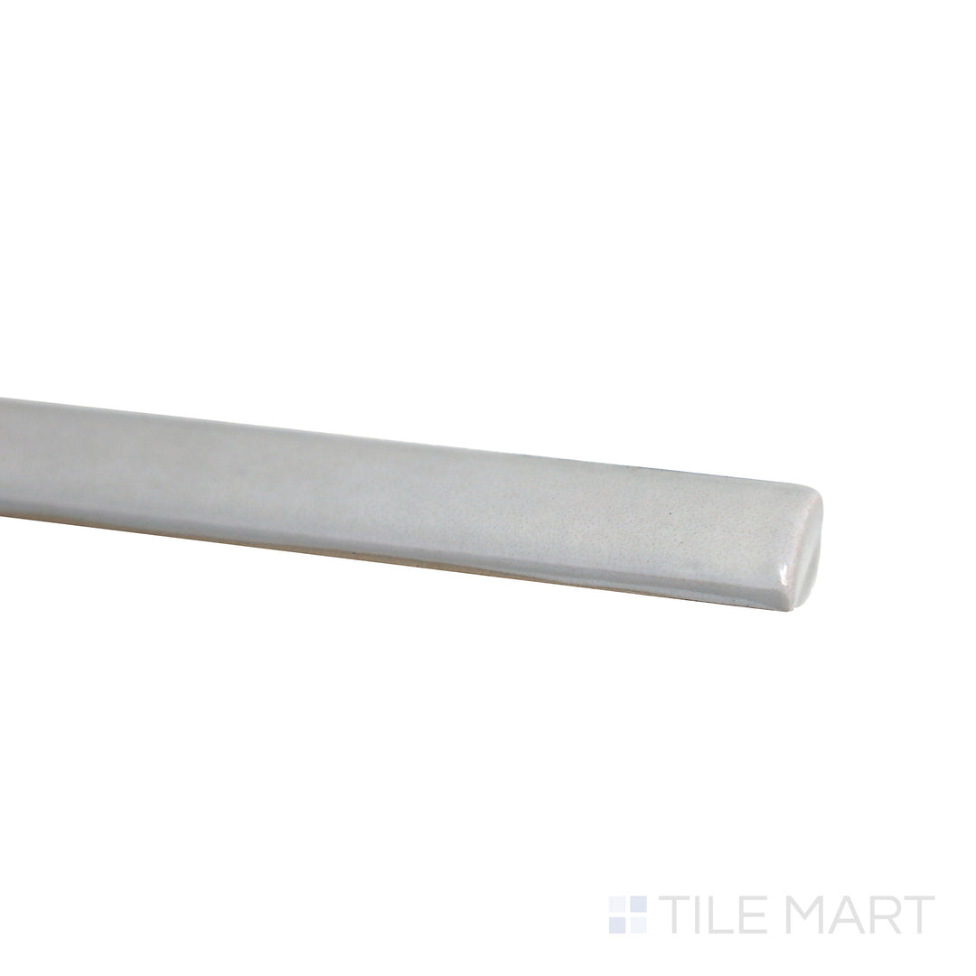 Slanted perspective of Village Silver Mist 0.5x8 glossy ceramic jolly tile, emphasizing its soft silver-gray color, sleek polished texture, and modern trim design.  