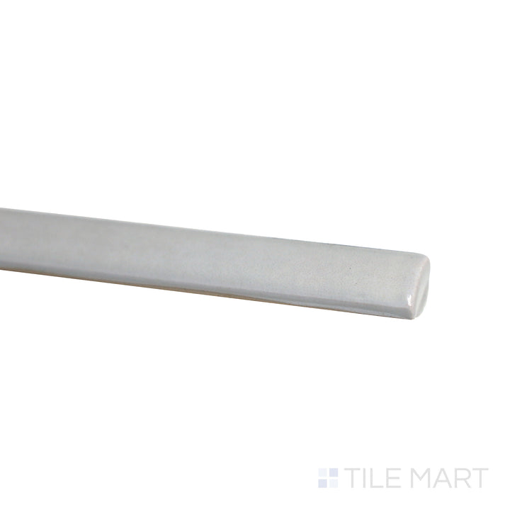 Slanted perspective of Village Silver Mist 0.5x8 glossy ceramic jolly tile, emphasizing its soft silver-gray color, sleek polished texture, and modern trim design.  