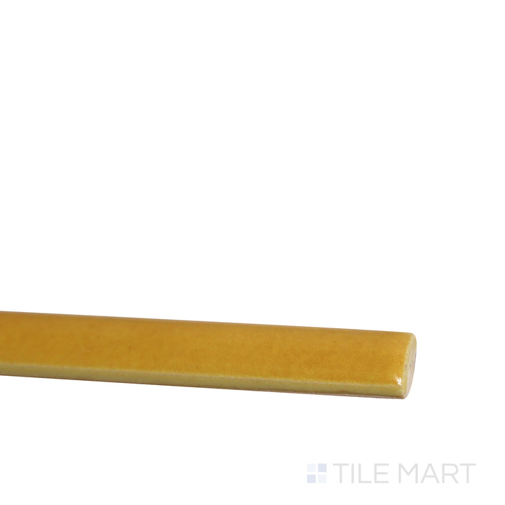 Angled view of Village Tuscany Gold 0.5x8 glossy ceramic jolly tile, featuring its warm golden tones, high-gloss surface, and refined trim layout.  