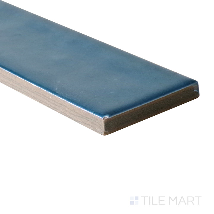 Angled shot of Calpe Blue 2x6 glossy porcelain tile, featuring a deep blue shade, a reflective glossy finish, and a sleek rectangular shape.  